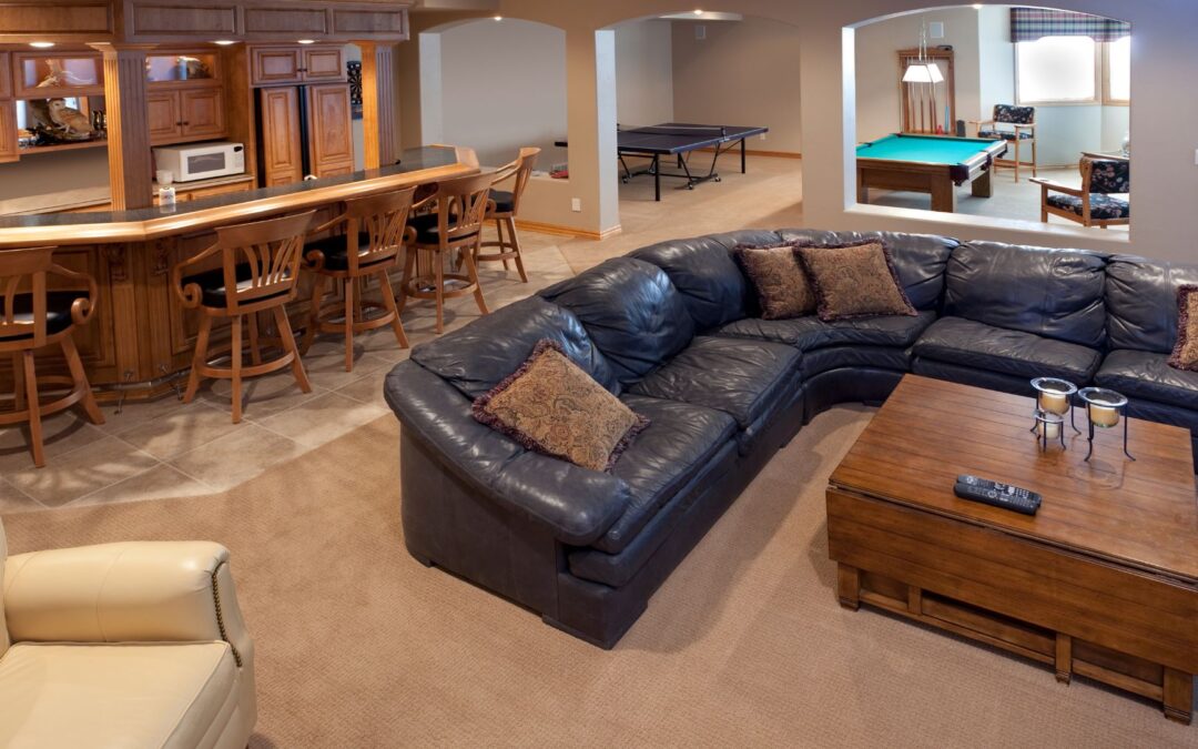Basement with a black couch, pool table, and other furniture.